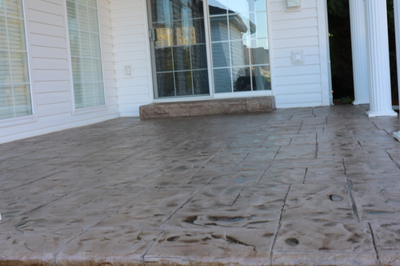 Stamped concrete patio outside of Kalamazoo, Michigan with a sliding door and concrete step.