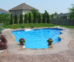 Outdoor pool in Portage, Michigan with stamped concrete and landscaped backyard.