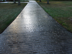 Long driveway with a gray brick stamped design performed by Kalamazoo stamped concrete.