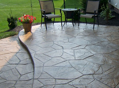 Stamped patio and patio chairs with a flower pot at a home.